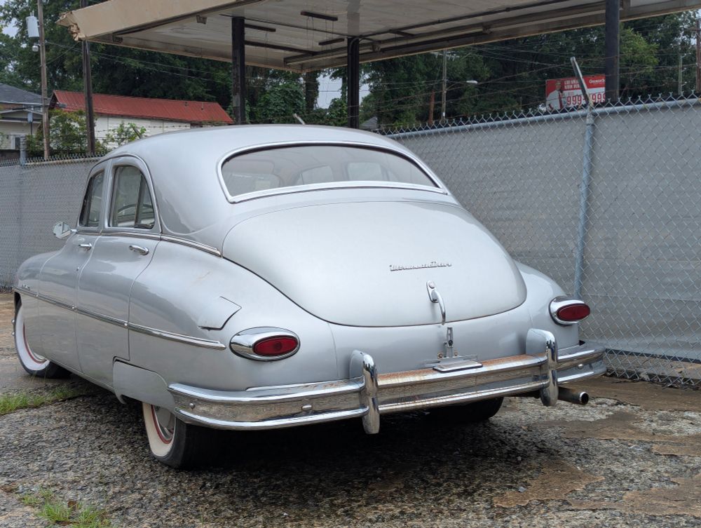 Rear angled view of a 1949 or so silver Packard vehicle