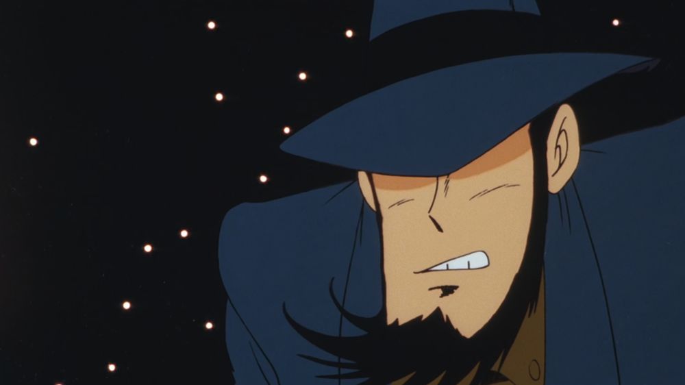 A handsome man with a hat and a beard, surrounded by stars, clenching his teeth