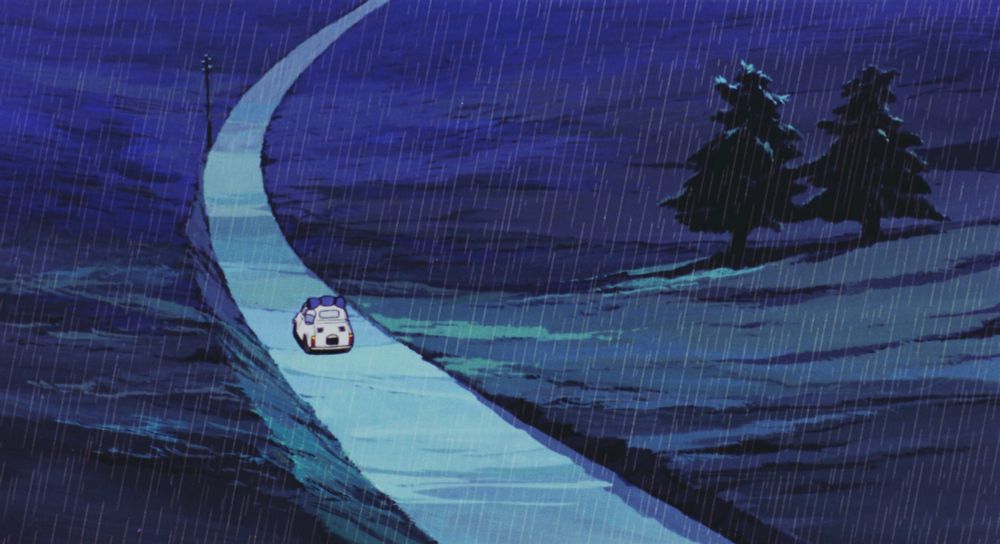 A Fiat 500 on a small, windy road in the rain.