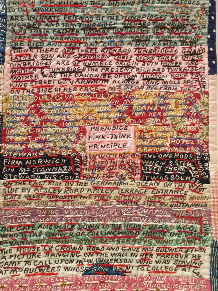 A hand stitched sampler in many colours (including greens pinks, yellows and blacks) with continuous prose, written in capitals, some of which is underlined. In the centre of the image is a pink box with the words "Prejudice Pink-Think Principle" hand stitched on it. 