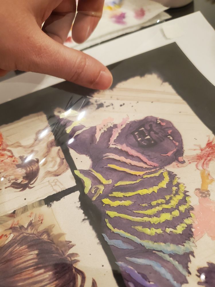 A process photo showing the colors for a comic panel done in acrylic paint on clear Duralar plastic film. The film is being lifted slightly, so the paint casts a shadow onto the art beneath.