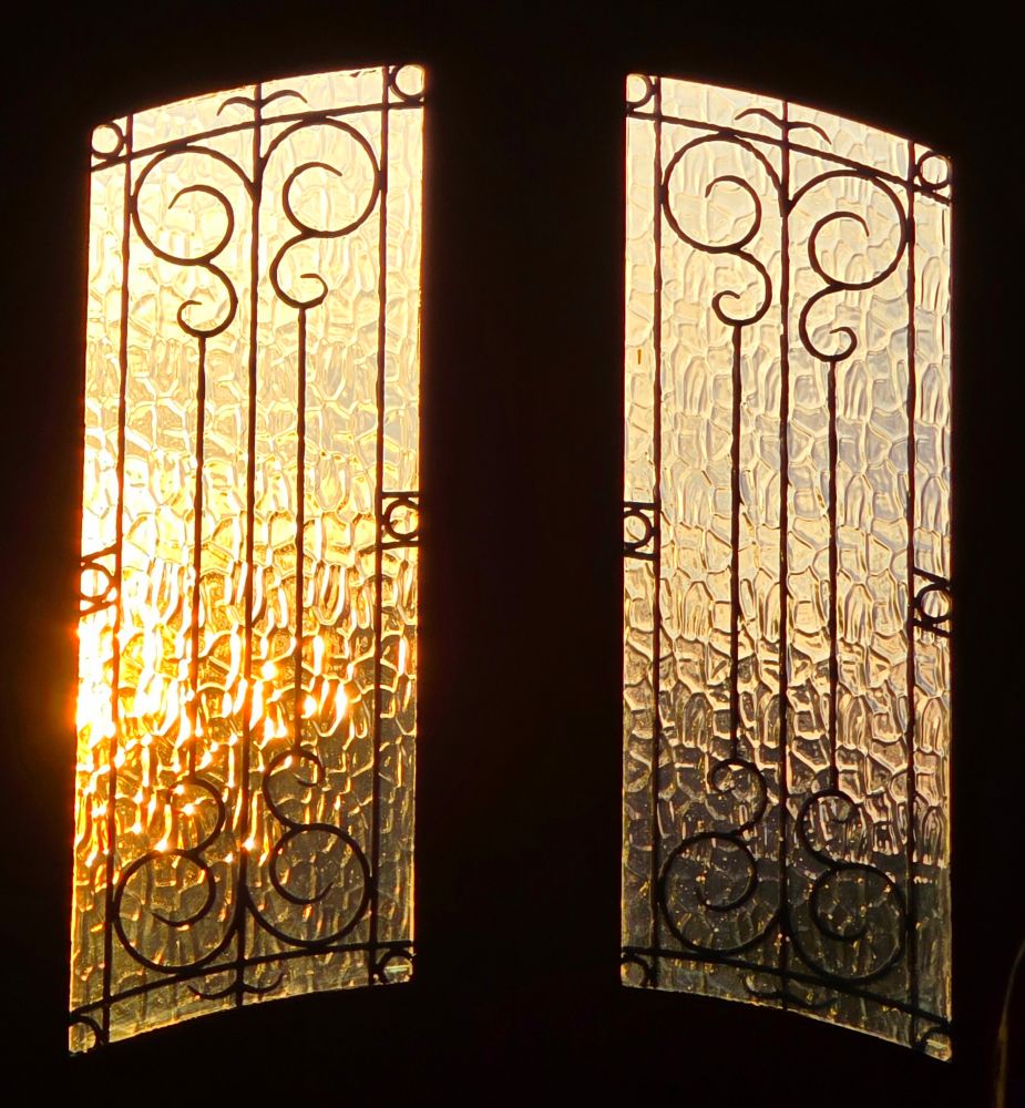 A golden sky seen through the frosted windows of a wooden double door