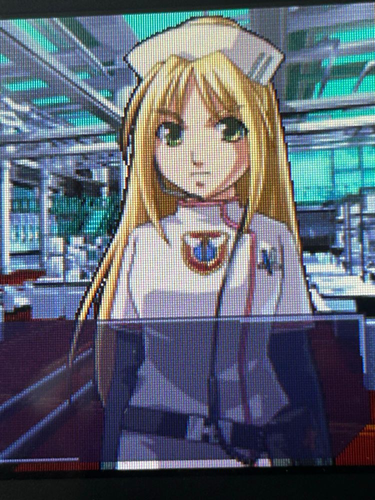 nurse angie from trauma center: under the knife for nintendo ds. she’s a blond anime girl with green eyes and long flowy hair. she’s making a determined expression but due to the cutesy artstyle she kinda looks like she’s pouting. she’s wearing a futuristic looking nurse uniform and hat. the image is a photo of the nintendo ds display, so the lcd pattern of the individual pixels is somewhat noticeable. 