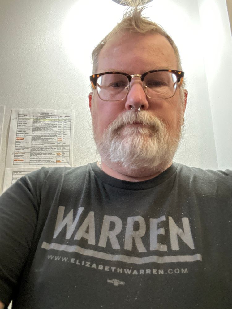 Blond, gray bearded nerd wearing an Elizabeth Warren tshirt on MLK Day 2025. 