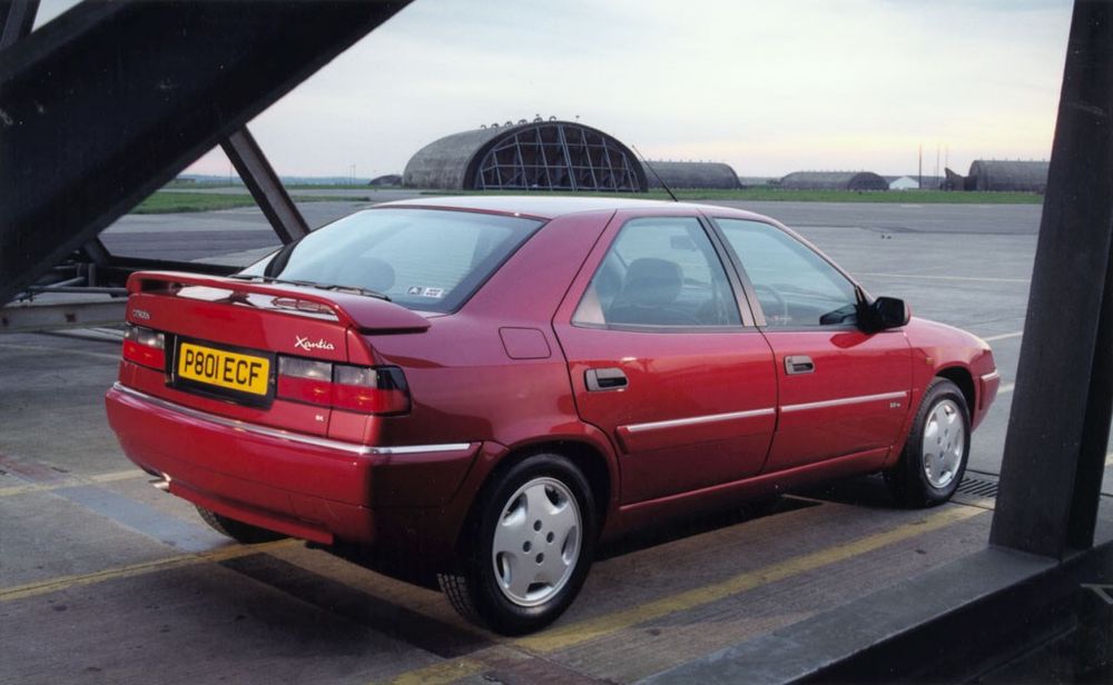 A pre-facelift Citroen Xantia in metallic red on an airfield