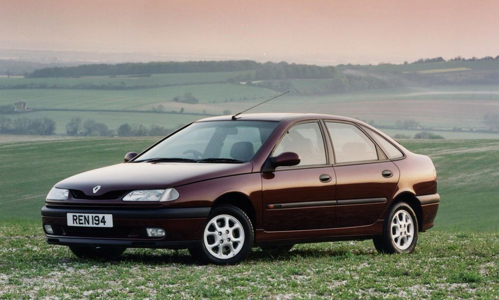 A Mk1 Renault Laguna in burgundy, in a field with rolling hills behind, at dawn