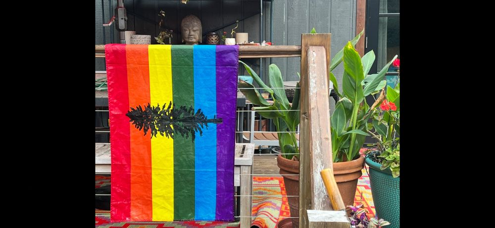 Picture of an LGBT version of the Cascadia Flag. Northwest evergreen tree on rainbow background