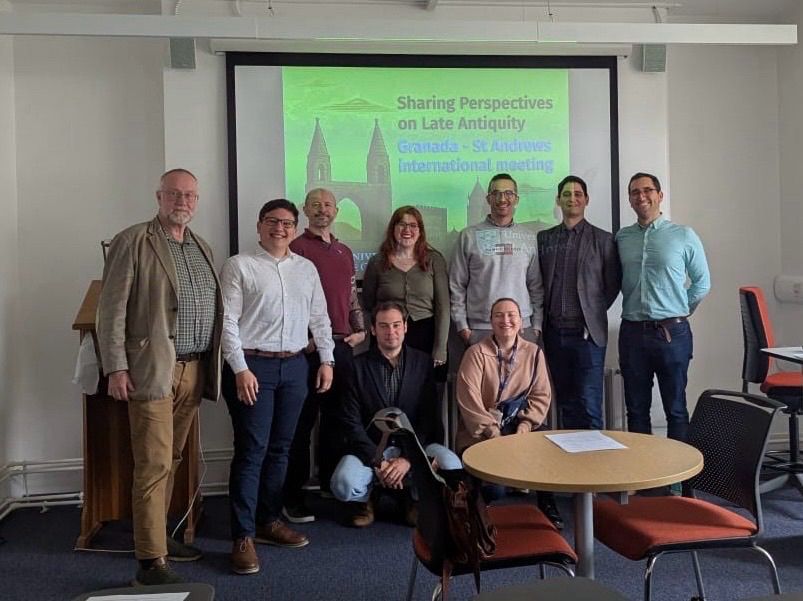Group photo of nine people in front of a projector screen with the graphic / title of the workshop projected onto it 