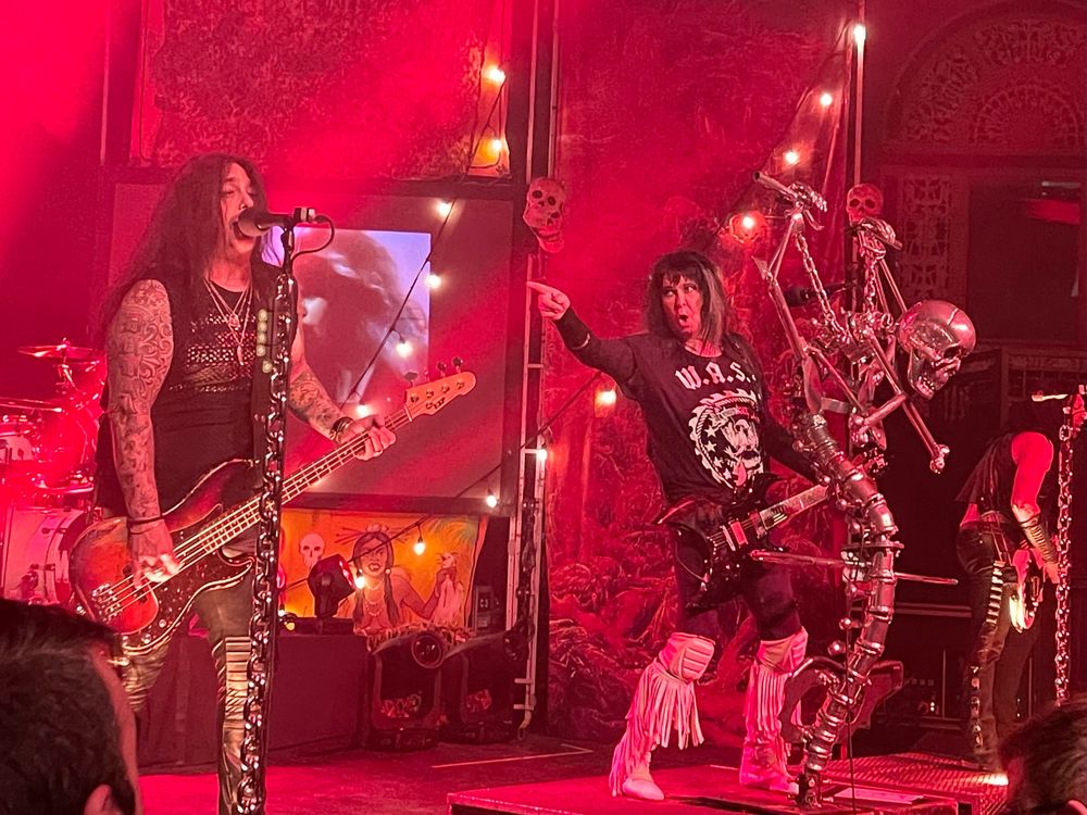 Picture of Blackie Lawless of the band WASP pointing at another band member. The lighting is red.