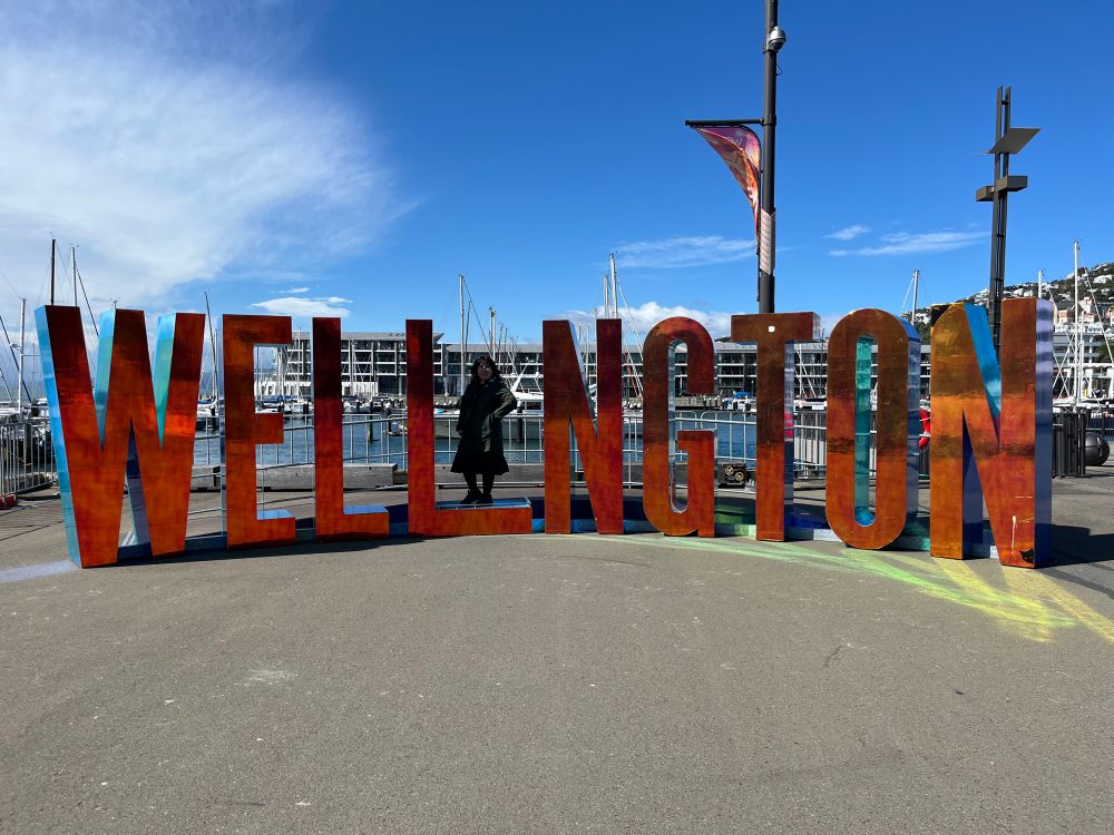 Photo of Wellington sign. A person stands in the middle to create the I in Wellington. 