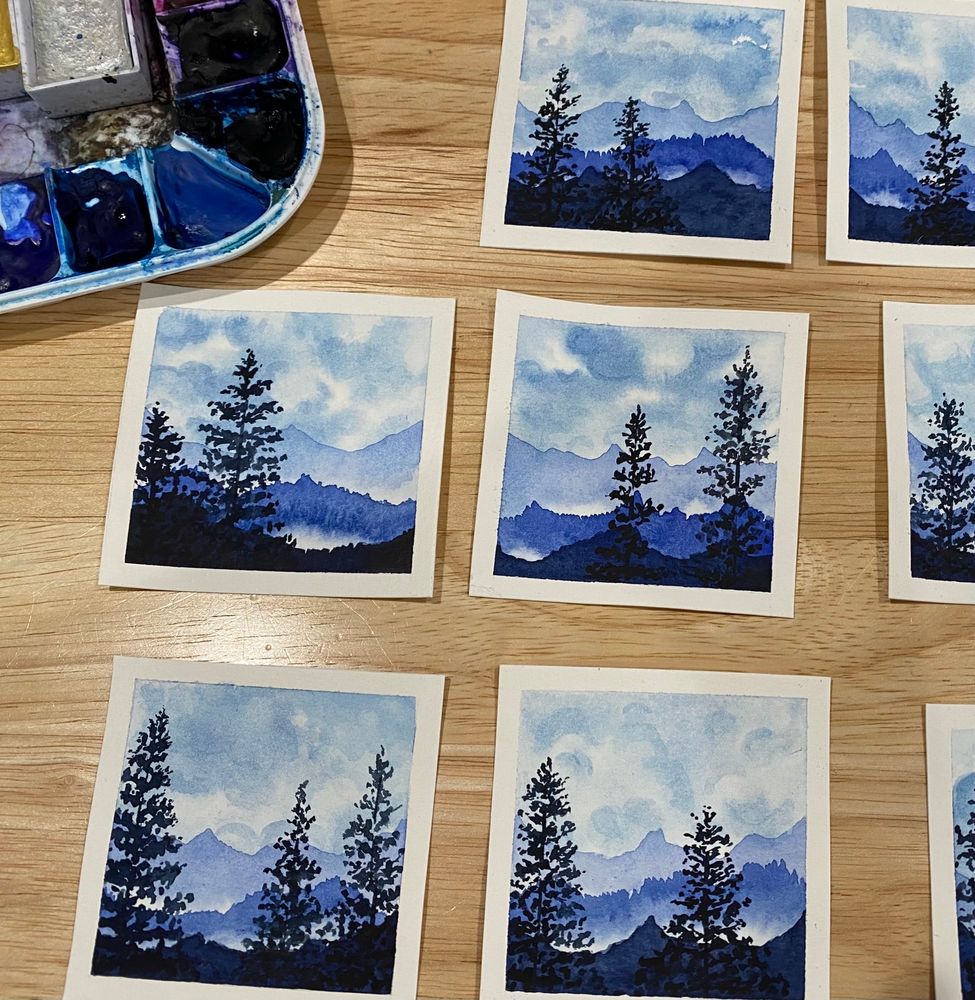 Mini 3x3 blue monochromatic watercolor forest/mountain-scape next to a watercolor pallet 