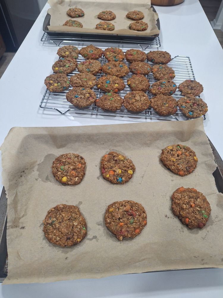 Two batches of oatmeal cookies-- one cooling on a rack, the other still on a baking pan.
