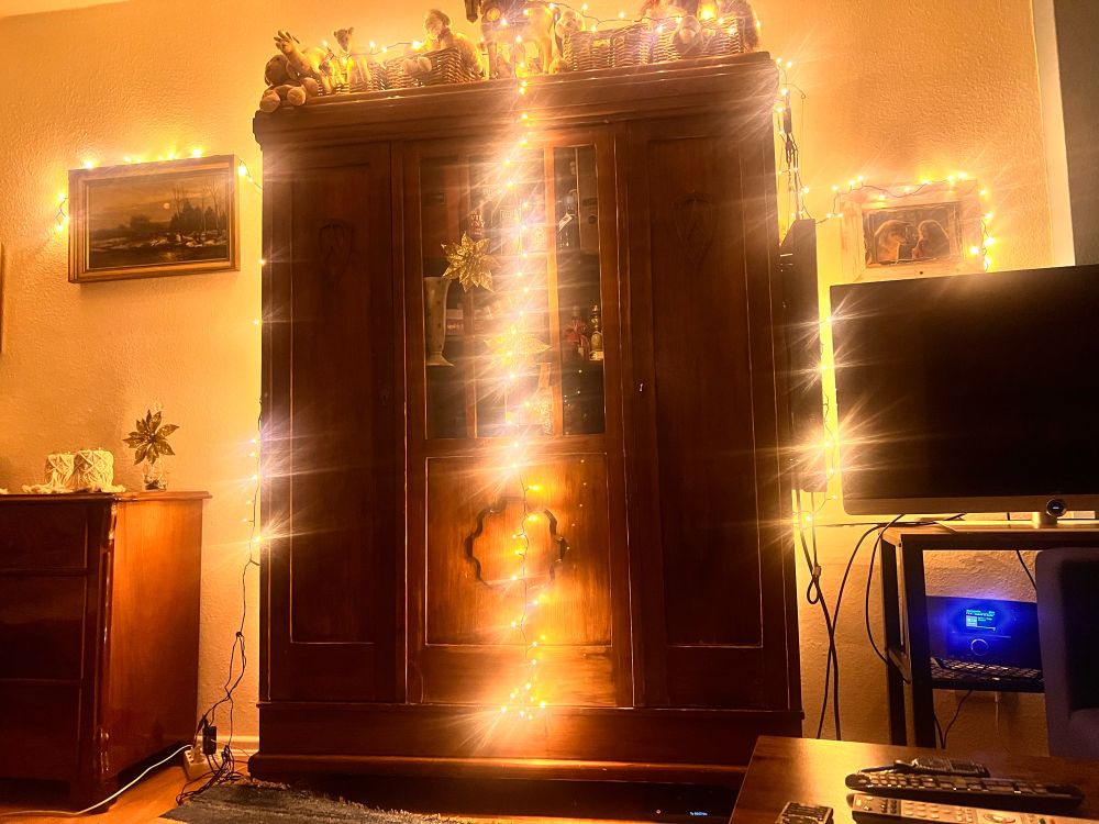 Ein Wohnzimmerschrank mit sehr viel Lichterkette geschmückt.
