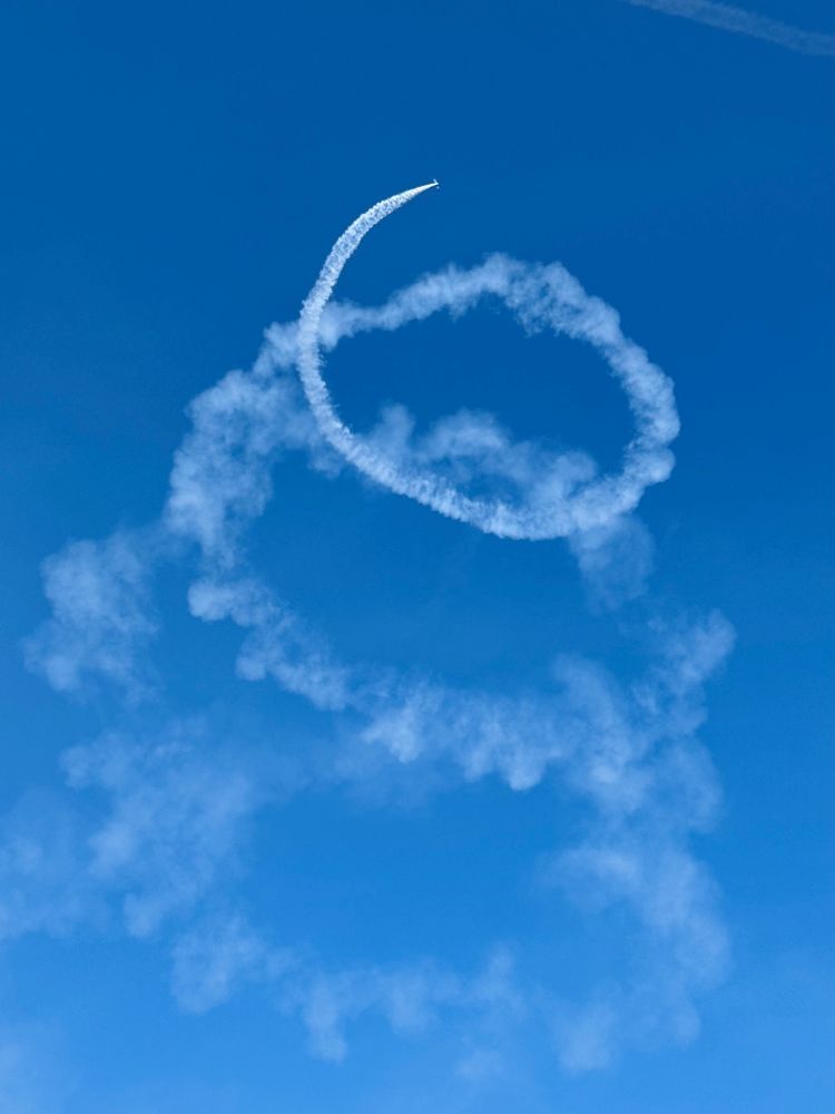 Small plane at the top of a large spiral of smoke