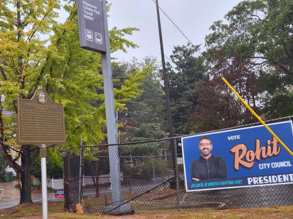 "Noon Under the Trees" Battle of Atlanta  historic marker next to "Atlanta is Worth Fighting For" campaign sign.