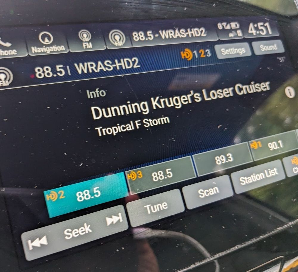 HD radio screen showing song title Dunning Kruger's Loser Cruiser by Tropical F Storm.