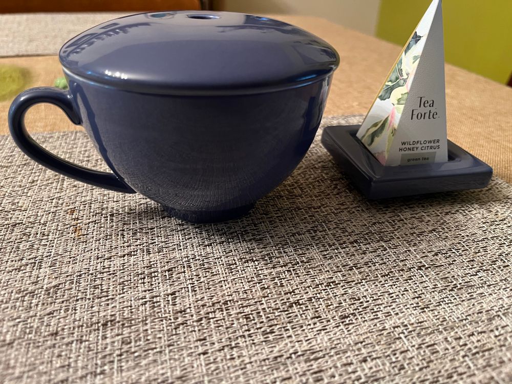 Blue tea cup with triangle teabag on teabag stand next to it