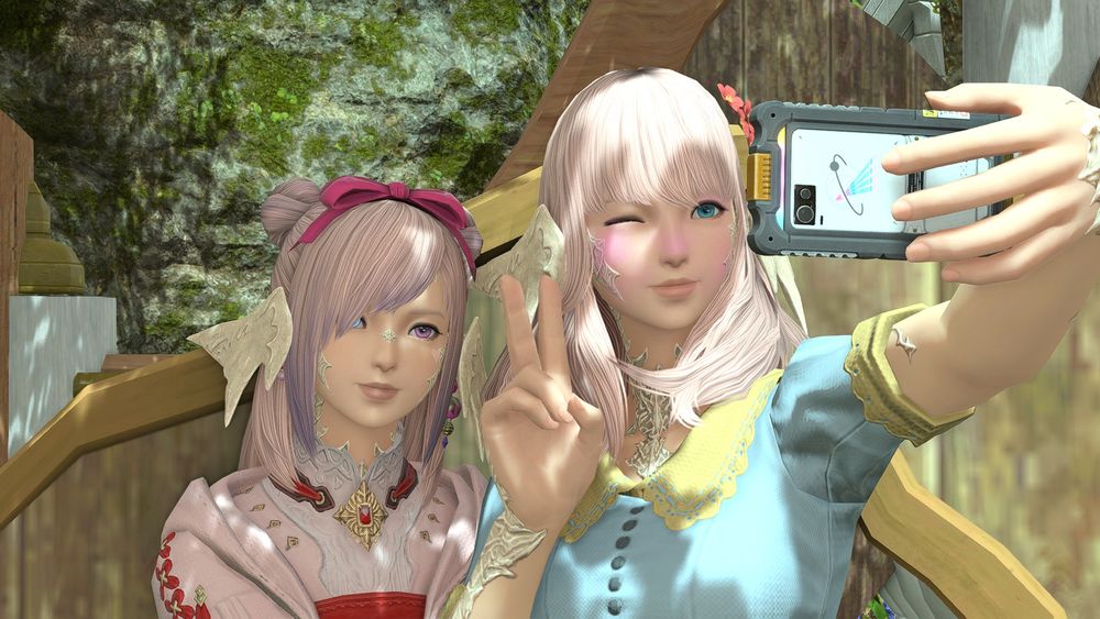 two pink haired au ra, one is taking a selfie while the other sits behind her.