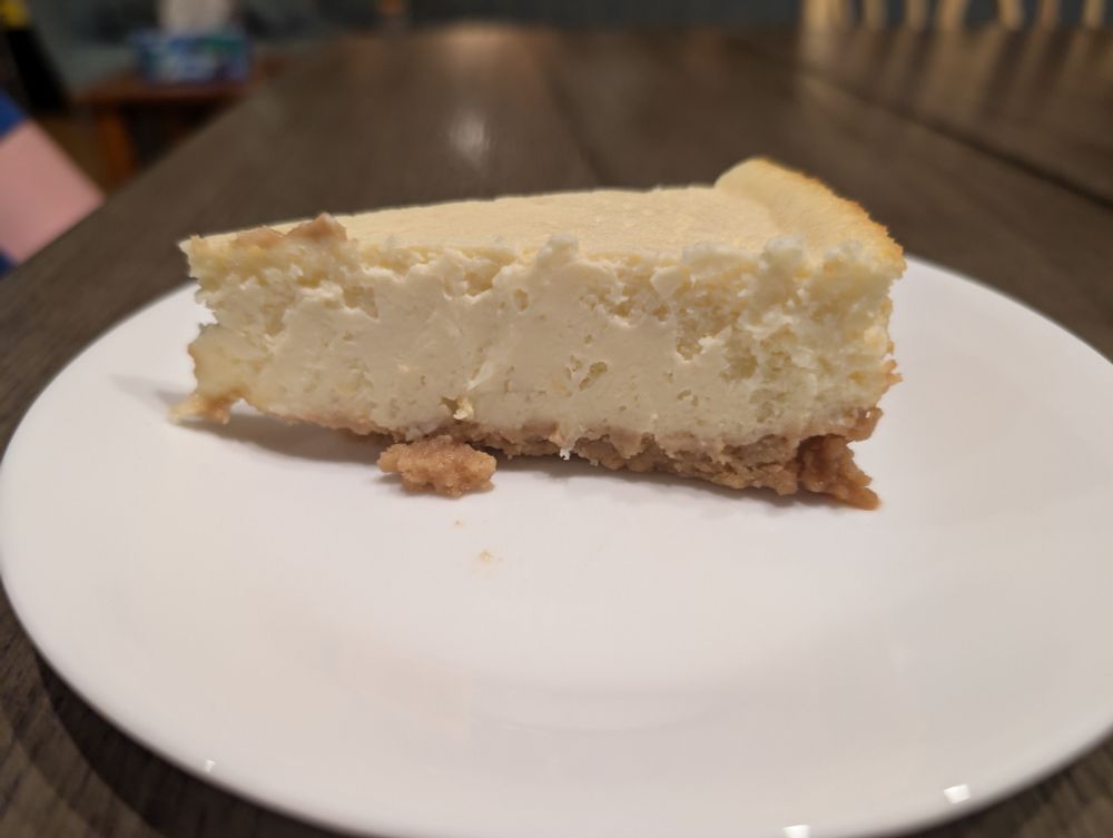 A cream colored Yuzu cheesecakes with golden sandwich cookie crust on a white plate