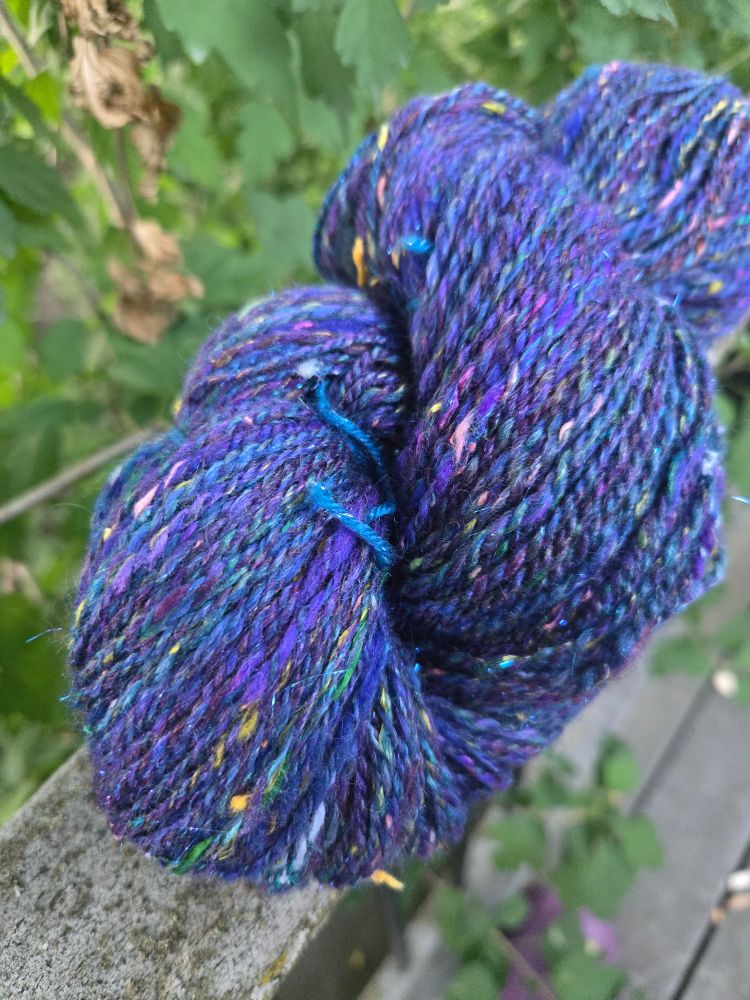 And a closer view of the same yarn from prior pics, showing the same flecks of pink, blue, and yellow, but also, shots of green and more intense purple. A hint of sparkle is barely visible. 