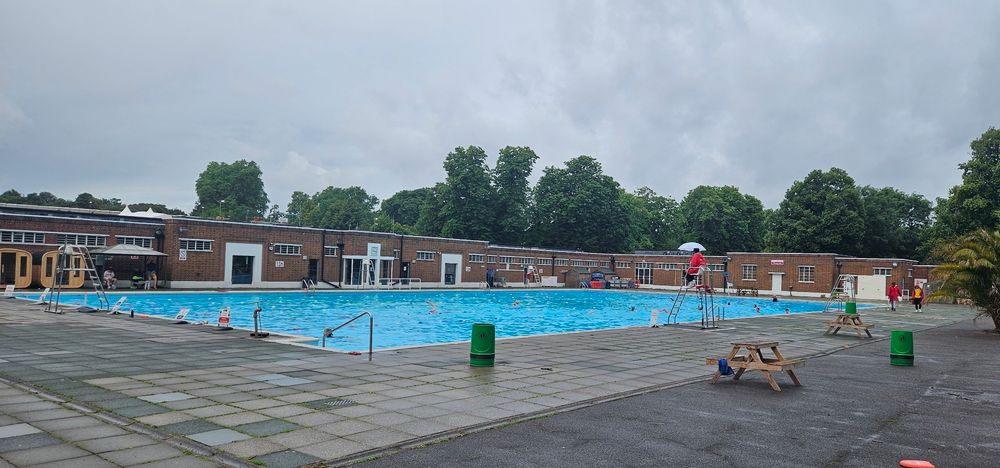 Brockwell Lido looking bright and blue under a leaden grey sky.