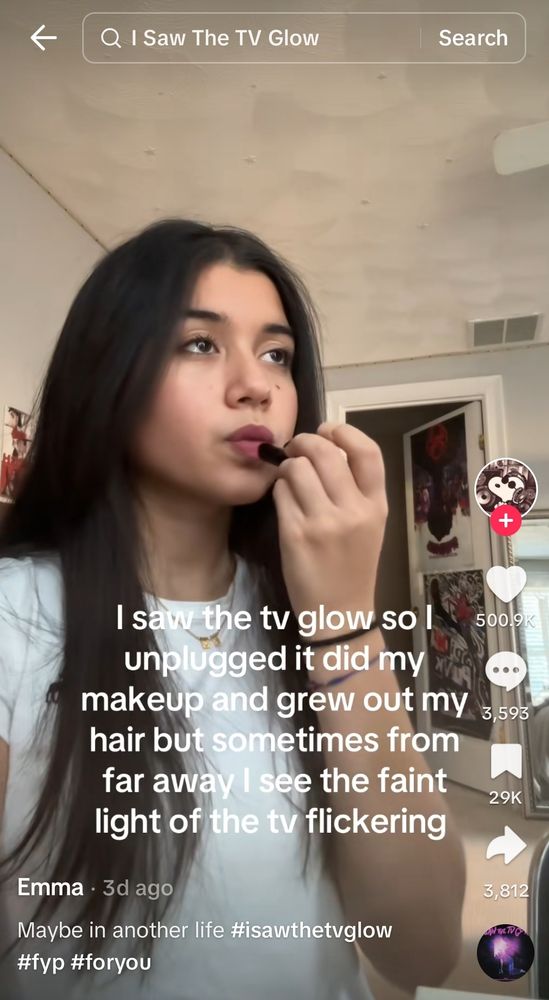 A screenshot of a tiktok of a femme presenting person putting on lipstick with text "I saw the TV glow so I unplugged it, did my makeup and grew out my hair but sometimes from far away I see the faint light of the tv flickering" with the caption "maybe in another life" beneath it