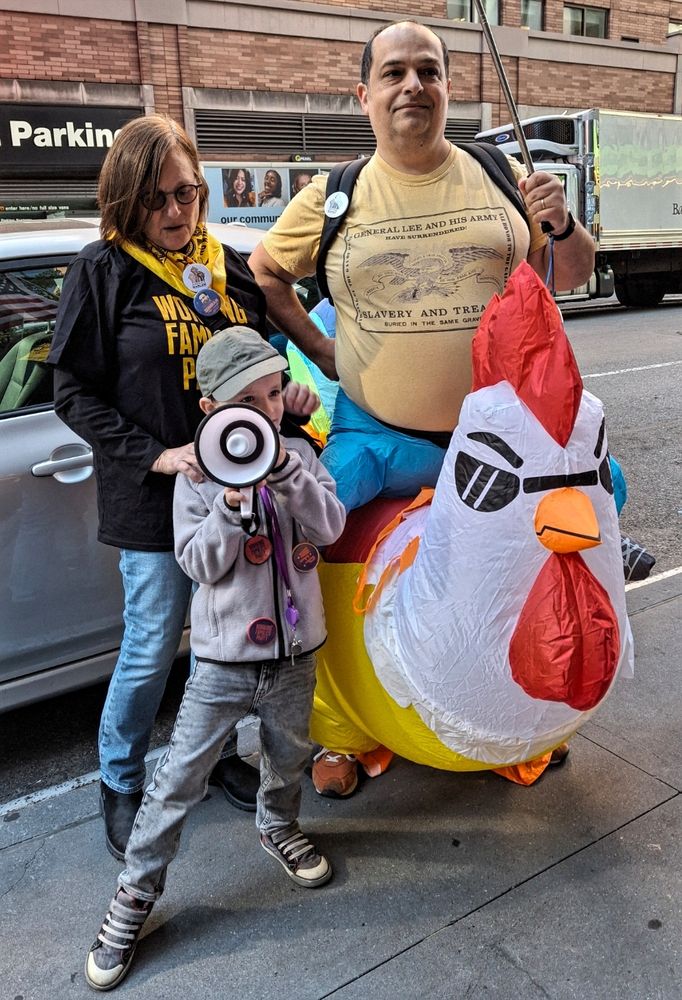 Man wearing inflatable chicken and boy with bullhorn leading a chant