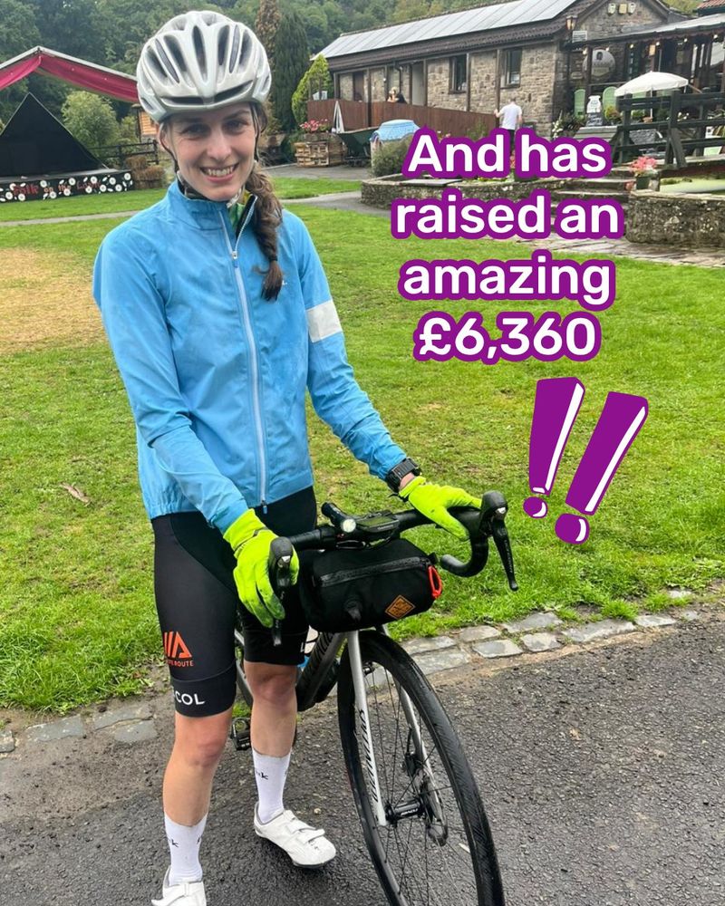 Photo of the young white woman, holding up her bike, and looking at the camera smiling. She stands in front of a bright green lawn. She wears a silver cycling helmet, a light-blue jacket, black cycling shorts and white trainers and socks. Text to the right is white with a purple border, reading 'And has raised an amazing £6,360'.