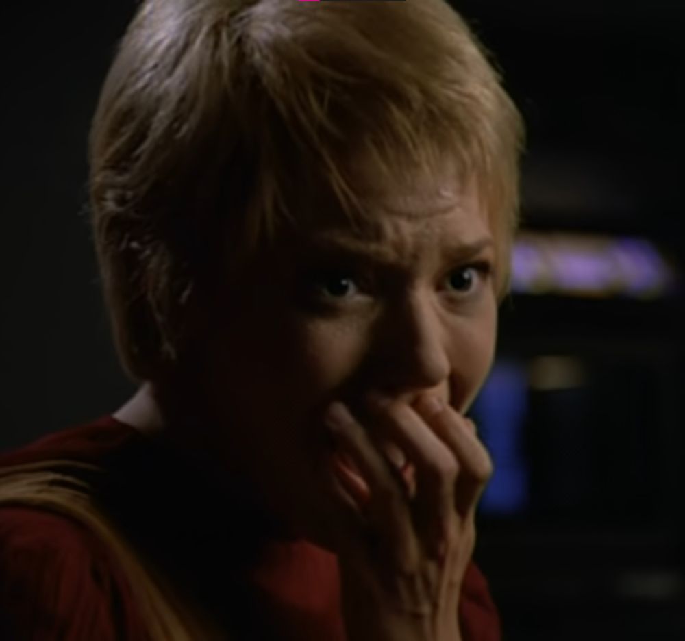 a blonde lady with her hand over her face, she is very very scared & appears to be screaming. her name is Kes & yes, she is screaming, because she showed her teacher a cool trick the new cool kid showed her & she almost roasted him from the inside in seconds