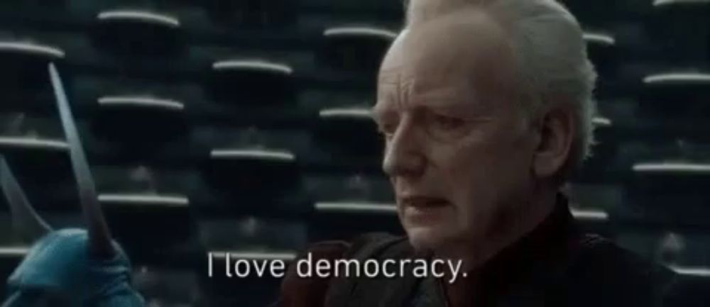 a man is holding a pair of scissors in his hand and saying `` i love democracy '' .