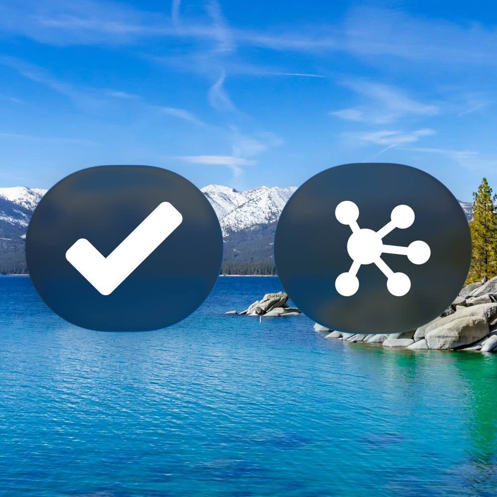 Liquid Glass buttons featuring glyphs representing OmniFocus and OmniGraffle, floating over a background image of Lake Tahoe—alluding to Omni's roadmap and macOS 26 Tahoe. (The buttons are rendered in Dark Mode on beta 2.)