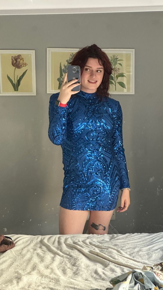 Nell in a blue sequins dress with red hair taking a selfie