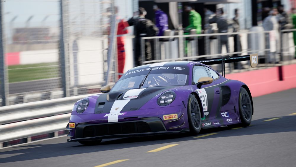 Porsche 911 GT3 R driving down the pitlane at the donington race track,
in the backgroud, mechanics standing on the pit wall