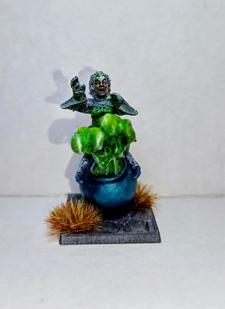 Halfling sauceror with glowing green stuff coming out of her cauldron. On a grey base with red/brown tufts