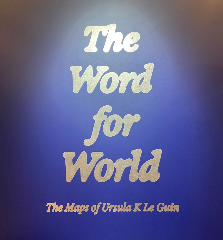 Sign for exhibition: The Word for World - the Maps of Ursula K. Le Guin, in silver on a blue background