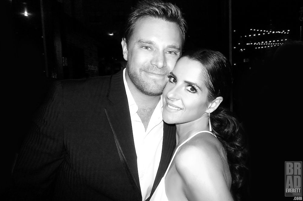 Black and white photo of a man and woman. The man has blonde hair. He's wearing a black tuxedo jacket with an open white shirt. He's holding a woman close in his arms. She has long dark hair pulled back. She's wearing a white evening gown. This is the late Billy Miller and Kelly Monaco. The two played NuJaSam and later Dream on GH. The photo was taken by the late Brad Everett Young. 