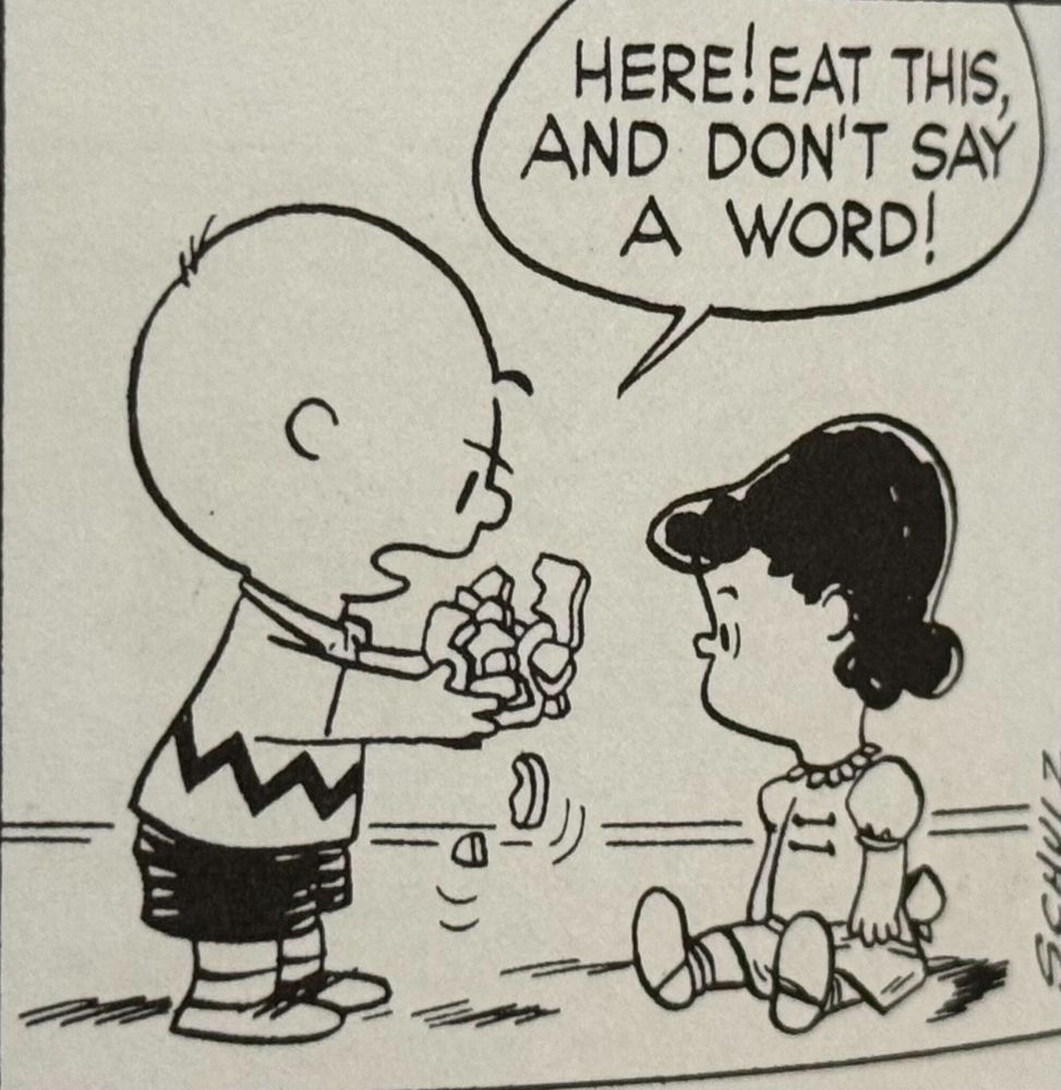 Charlie Brown hands a handful of scraps to Lucy and says "Here! Eat this, and don't say a word!"