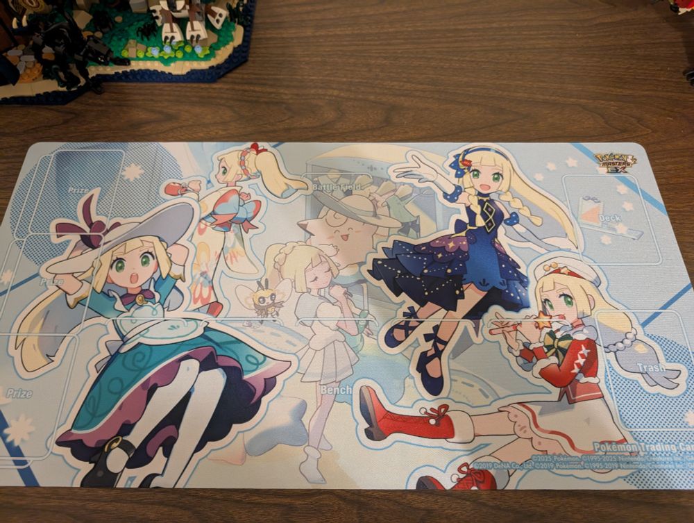 A pokemon TCG playmat depicting the alt outfits of Lilly in Pokemon Masters EX