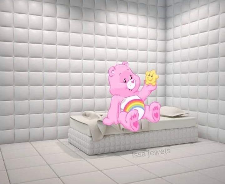 Bisounours rose avec arc en ciel sur le ventre, ayant un énorme sourire et tenant une étoile dans sa main 
Il est assis dans une chambre d'hôpital psychiatrique capitonnée dépourvue de tout sauf dans lit rudimentaire 
