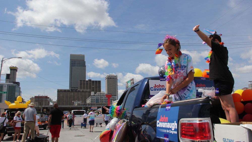 A truck with a John Cavanaugh for Congress sign on the side. In the background is the Omaha skyline. 