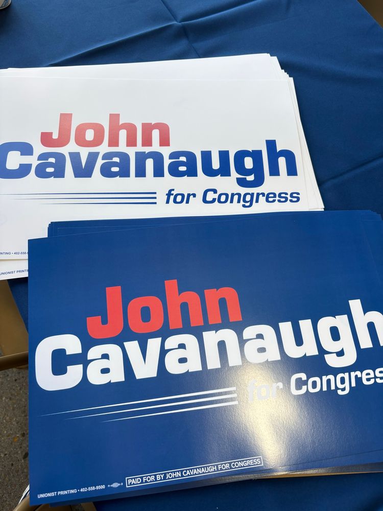 Signs on a table which say John Cavanaugh for Congress. 