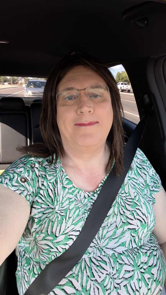 Melissa wearing a green on white floral print top, in my car headed out to do errands.