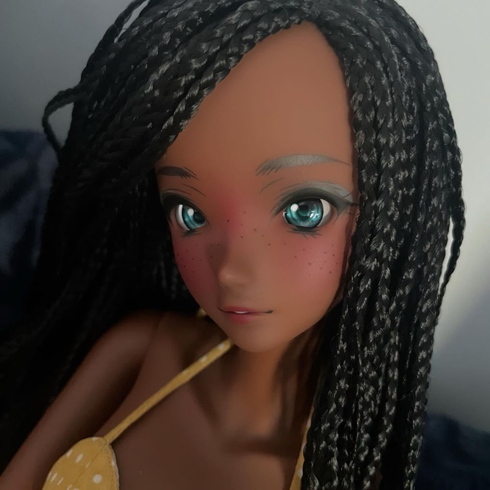 Smart Doll Fortitude in Coffee with black braided wig. A medium dark complexion mechanically jointed doll with a semi real anime style face with blue/teal eyes. 