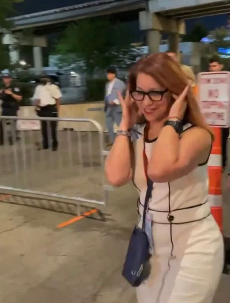 Woman covering her ears as someone reads the names of children murdered by Israel  