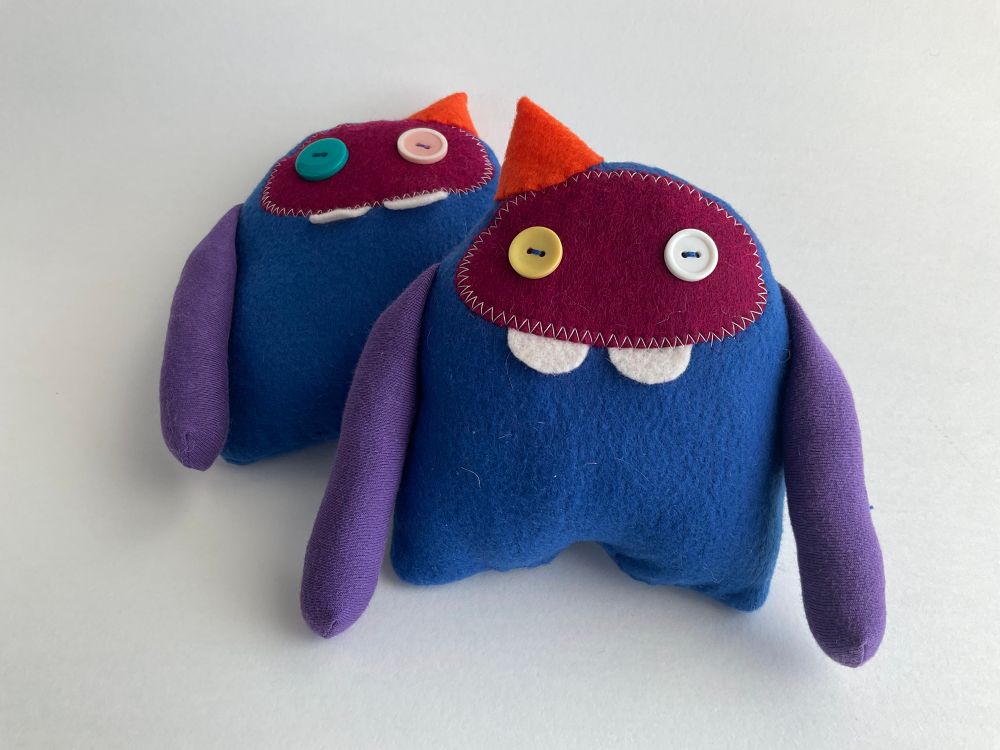 Two monster plush toys with buck teeth and party hats.