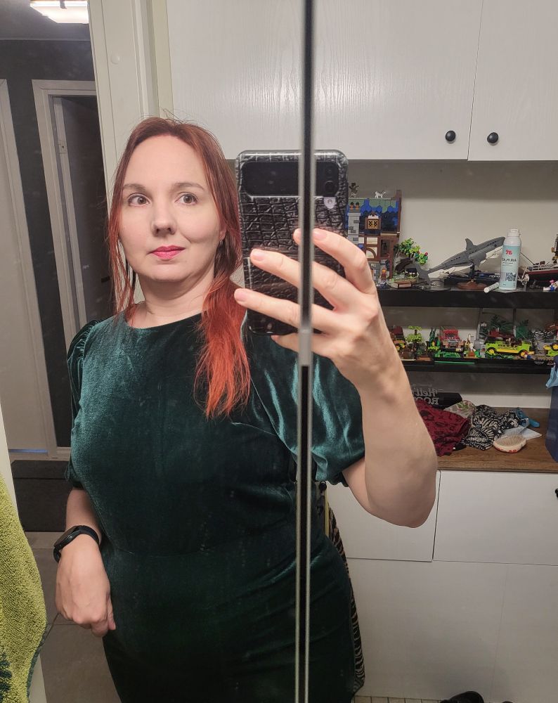 Omakuva nainen vihreässä mekossa. Taustalla legoja