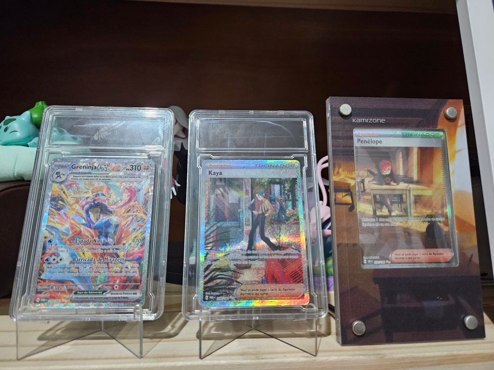Cartas Pokémon TCG expostas em displays em uma estante de madeira.