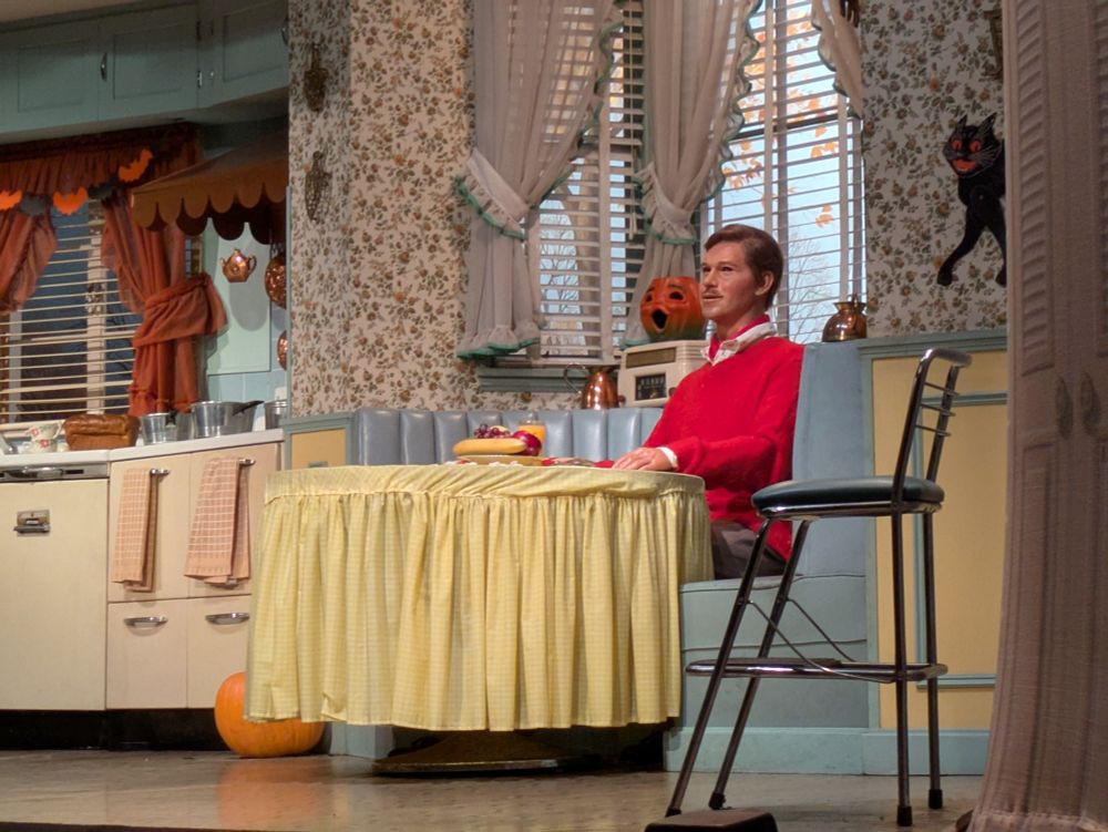The Carousel of Progress father in the 40s section of the show, wearing a red sweater at a kitchen table 
