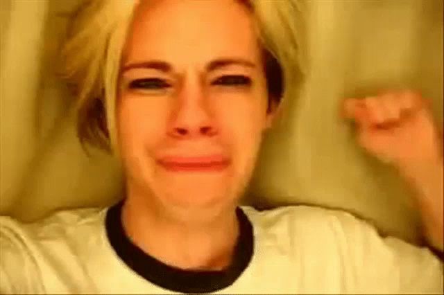 a woman is crying and making a funny face while wearing a white shirt .