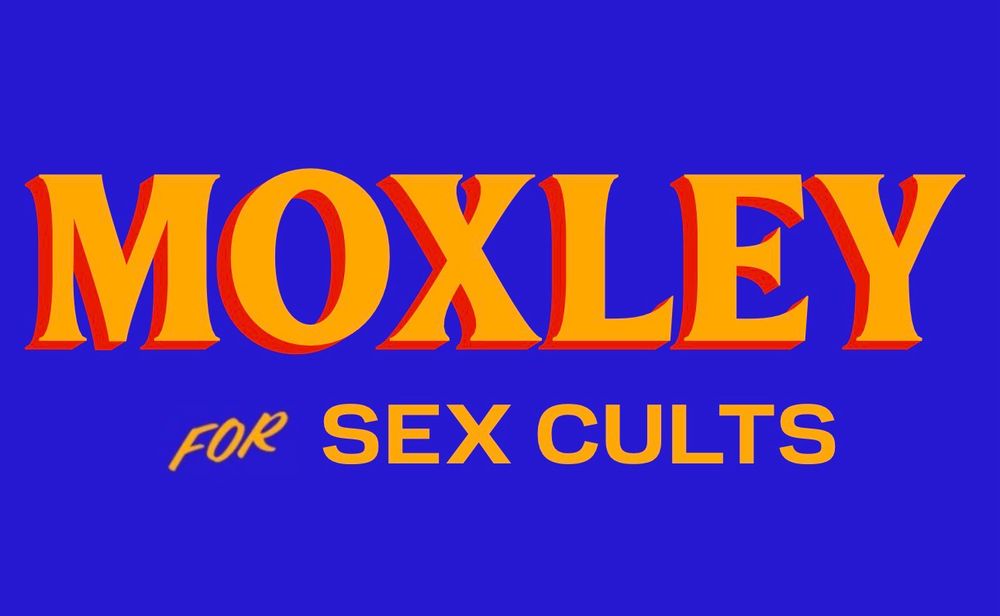 A sign that says Moxley for Sex Cults referencing the Death Riders stable in AEW which is a sex cult disguised as a faction which rewards success with praise and affection and punishes by having Wheeler Yuta spiral by growing his hair out mid-existential crisis